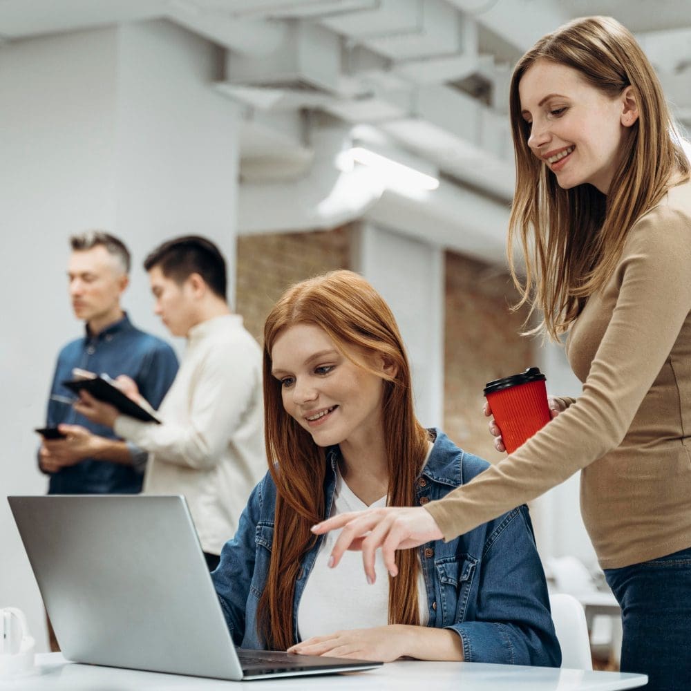 Two women engaging in local digital marketing on a laptop in an office setting.