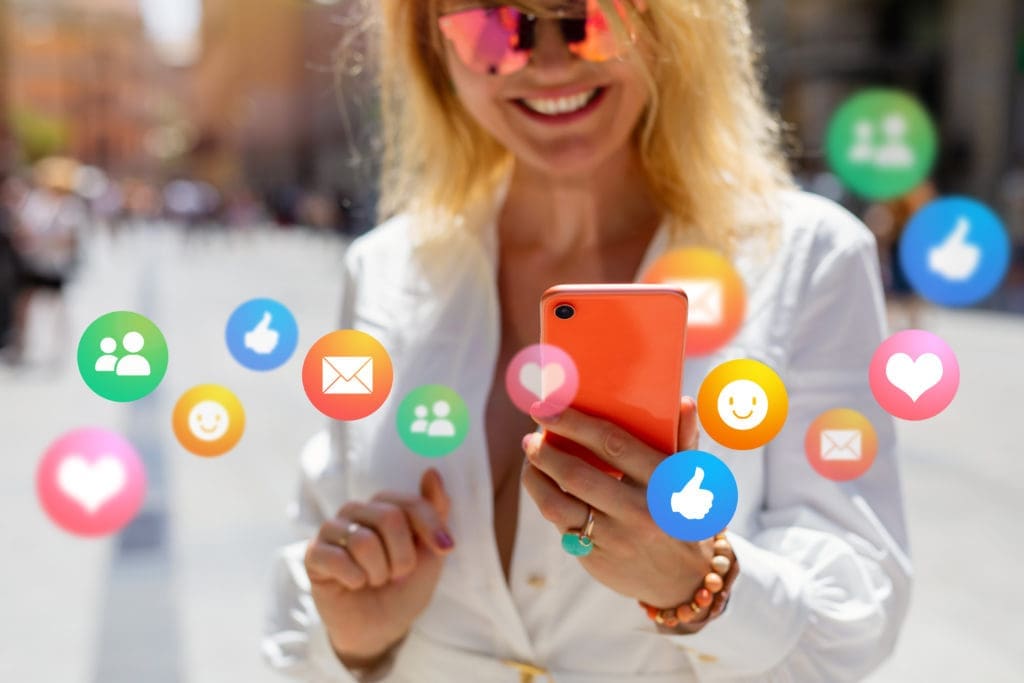 A woman holding a cell phone with social icons on it.